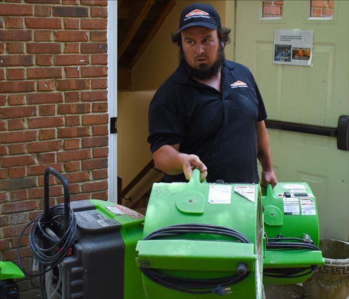 SERVPRO Male Tech carrying out green air movers from a building