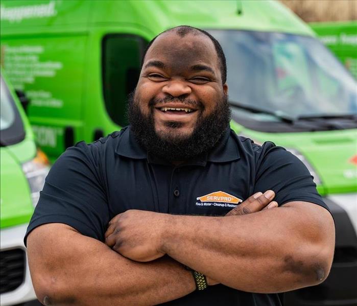 Arthur is an African American male wearing a black SERVPRO branded shirt in front of a green SERVPRO truck 